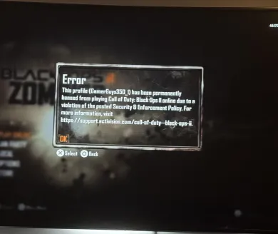 The same permanent ban notice photographed on a TV, shown over the Black Ops 2 Zombies menu